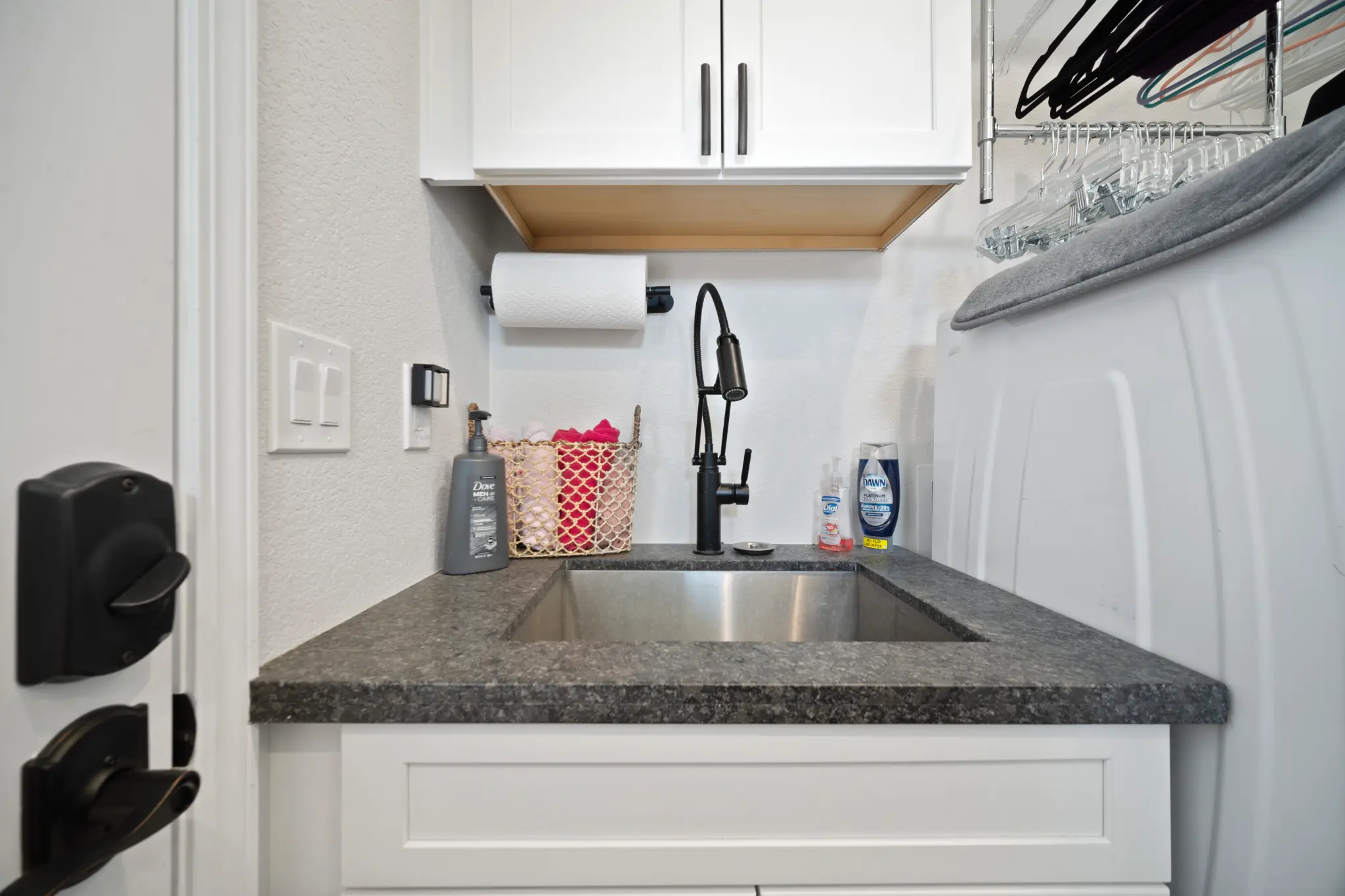 Laundry room sink detail with granite countertop and black pull-down faucet at Seven Pines Court home Damonte Ranch South Reno