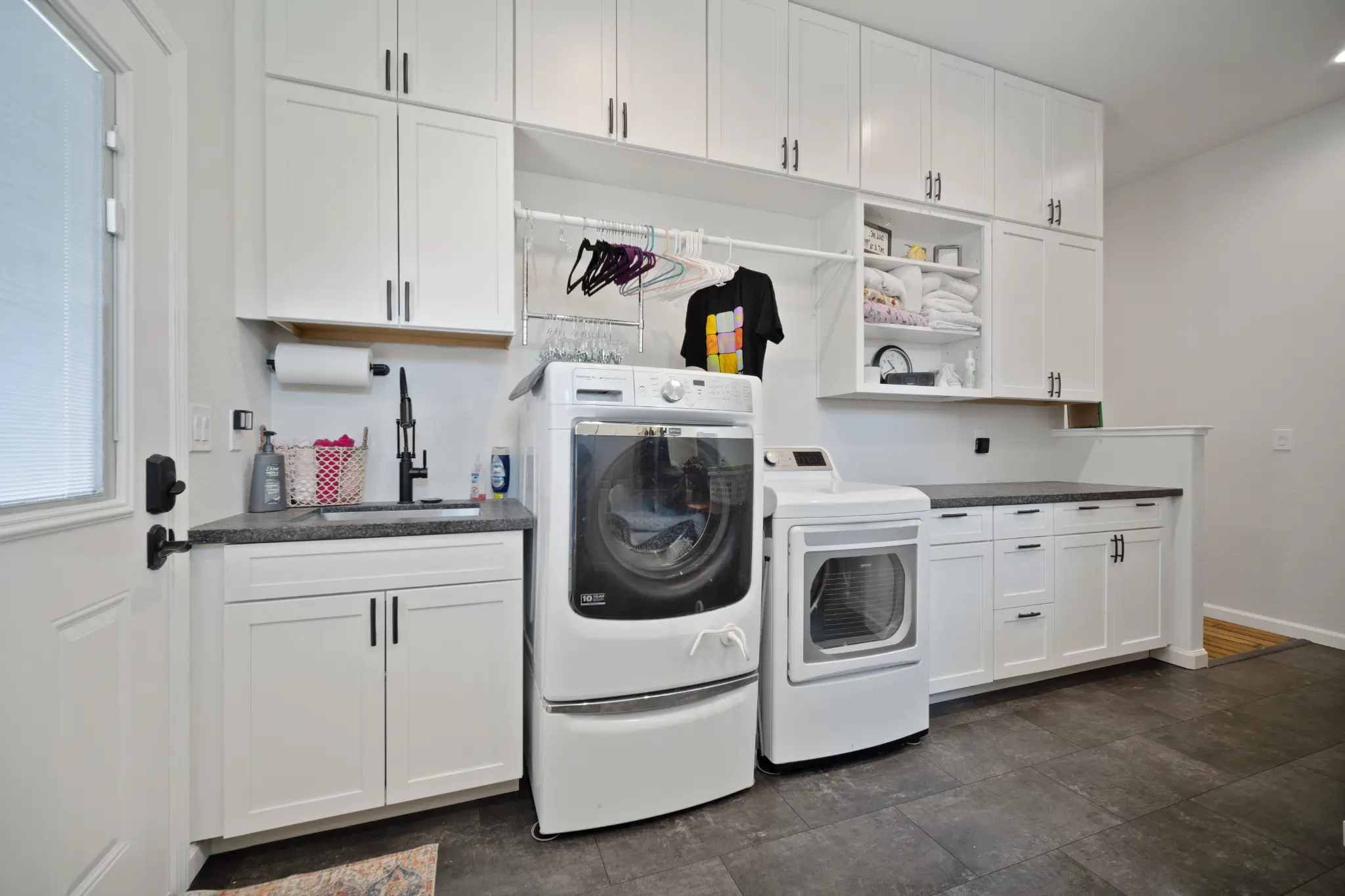 Full laundry room with washer dryer white cabinets and utility sink at Seven Pines Court home Virginia Foothills Reno Nevada